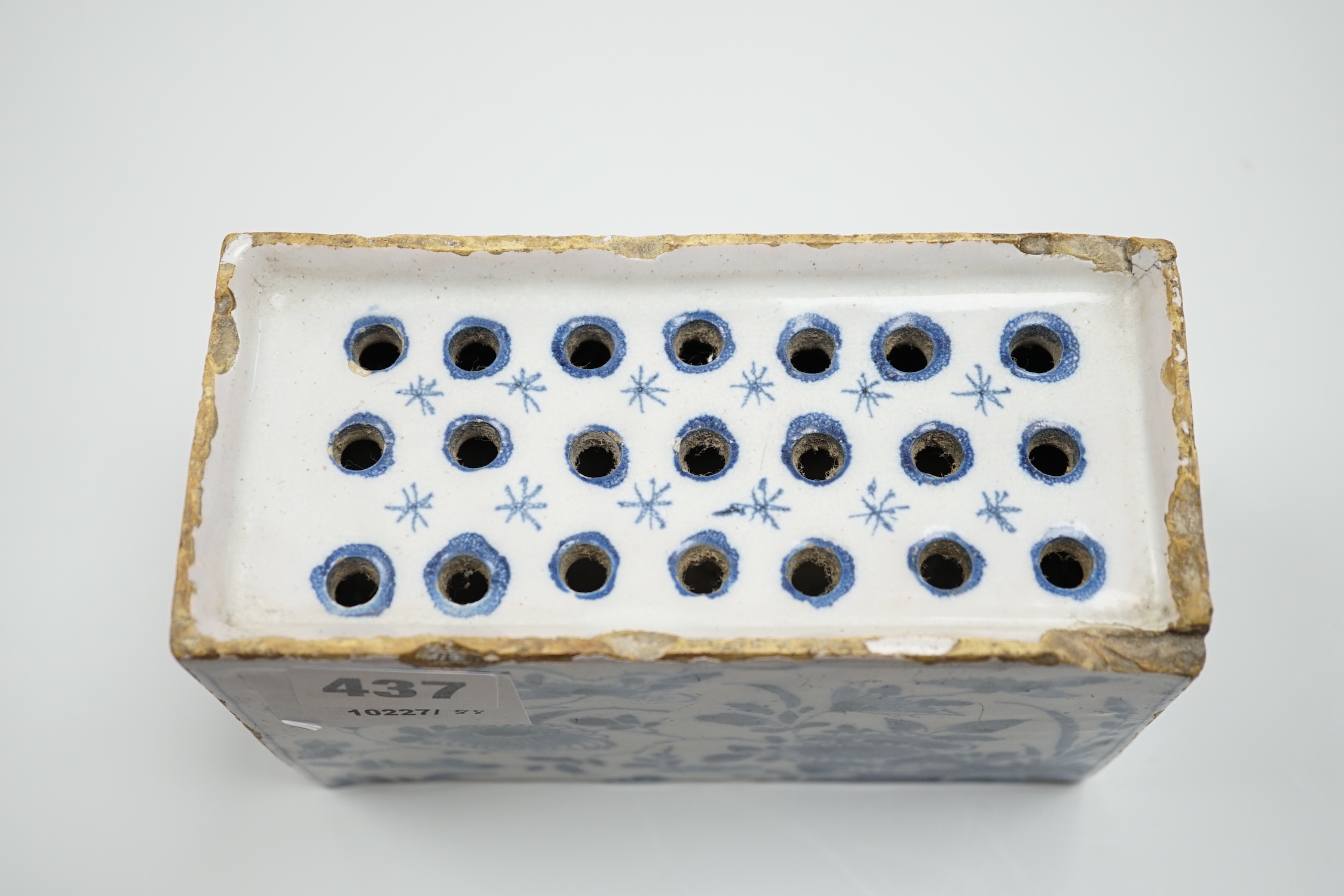 A mid 18th century English delftware flower brick, probably Lambeth, painted in underglaze blue with stylised chrysanthemums, 15cm wide